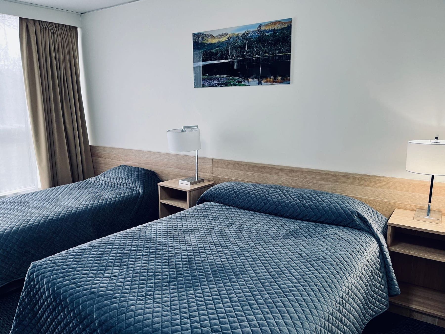 Twin guest room with 2 beds and Tasmanian landscape artwork at the Heemskirk Motor Hotel